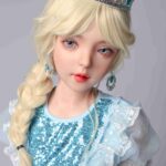 Realistična ženska lutka z blond lasmi, spletenimi v kito, modrimi očmi, oblečena v tiaro in modro bleščečo obleko, ki poudarja visokokakovostne, realistične poteze za družbo odraslih.