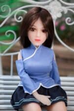 Realistic sex doll sitting on a bench, detailed female sex doll with brown hair and blue outfit, lifelike adult love doll for companionship and intimacy, high-quality sex doll mini from sexdollmini.com.