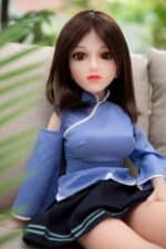Realistic sex doll with lifelike features, brown hair, and detailed facial expression sitting on a sofa, showcasing high quality and craftsmanship for adult satisfaction.