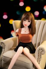 Realistic sex doll sitting on a beige armchair with a colorful blurred background, showcasing the perfect blend of lifelike features and premium craftsmanship for adult intimacy.