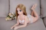 Silicone sex doll with realistic features, long blonde hair, and blue eyes, lying on a sofa with flowers in the background, designed for companionship and adult pleasure.