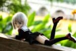 Realistinen anime-tyylinen nukke makaa ulkona puupinnalla eloisan vihreän kasvillisuuden taustalla. Täydellinen keräilijöille, jotka etsivät korkealaatuisia ja aidonnäköisiä seksinukkeja Sexdollminiltä.
