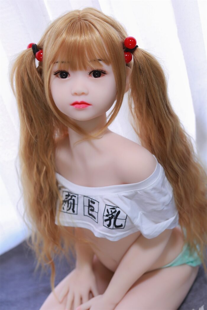 Arcadia Sex Doll6 Реалистичная секс-кукла с длинными светлыми волосами, уложенными в косички, одетая в белый топ с открытыми плечами и японскими иероглифами, создана для удовольствия и общения взрослых, от Sexdollmini.com.