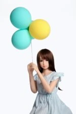 Tiny sex doll with realistic features holding pastel-colored balloons, showcasing lifelike details and high-quality craftsmanship for adult pleasure and companionship.