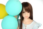 Realistic sex doll with brown hair and grey eyes, surrounded by colorful balloons, perfect for intimate companionship and high-quality doll experiences.
