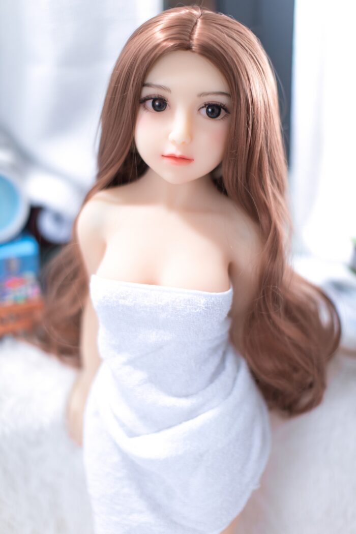 Realistic Sex Doll With Detailed Facial Features And Long Brown Hair, Designed For Intimacy And Companionship, Captured In A Bright, Cozy Room Setting.